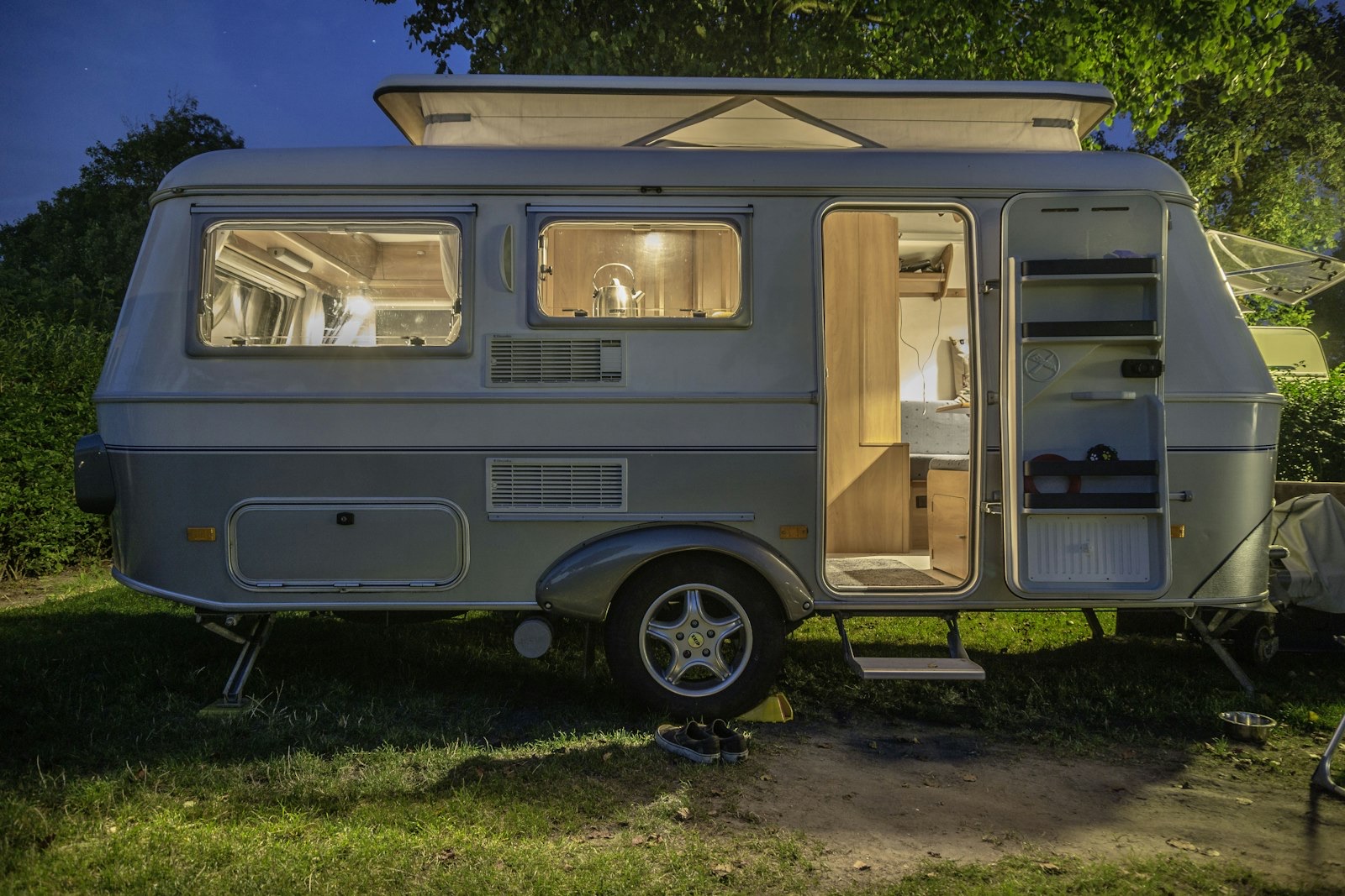 A caravan lit up at a grassy campsite at dusk — camping in New Zealand