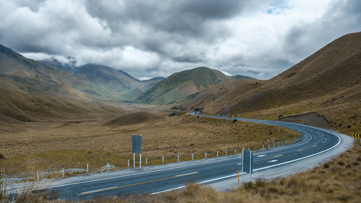 State Highway 8 winding through the golden tussock hills of the high country near the Lindis Pass between Omarama and Cromwell